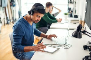 Shot of an attractive young man listening music on his tablet in an office.